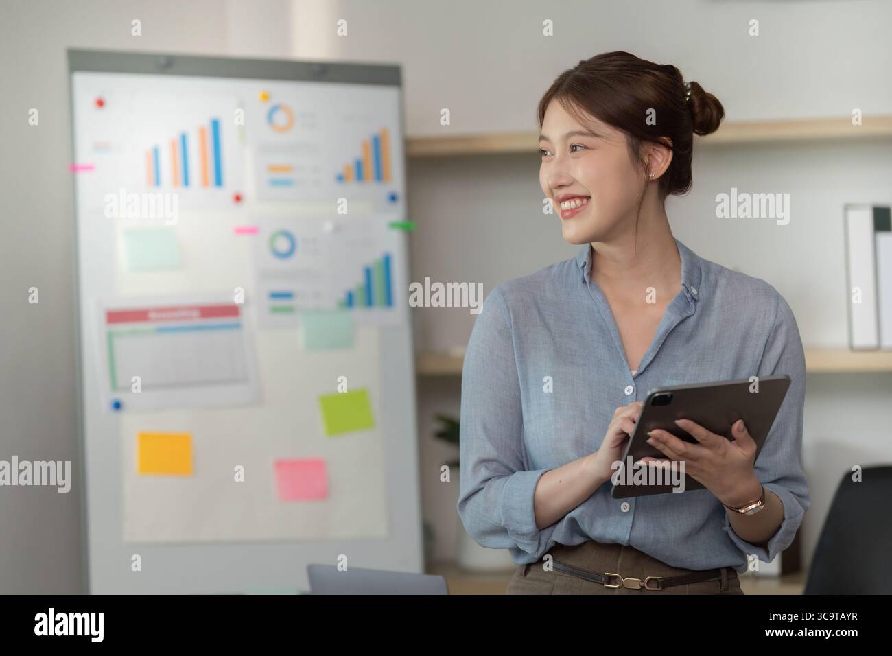 Professional woman analyzing data with tablet in modern office Stock Photo