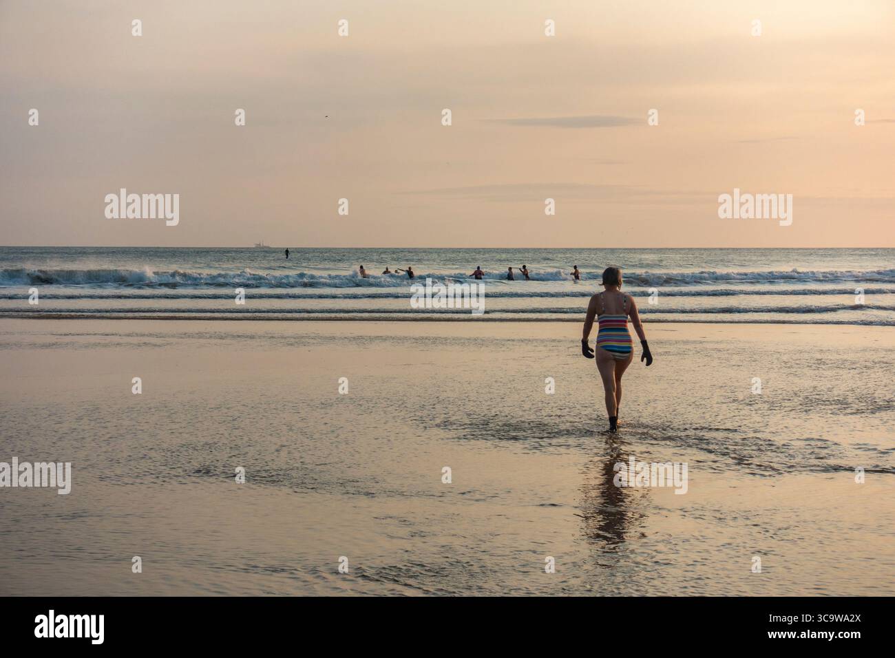 Swimmers heading out at sunrise at Saltburn by the sea, North Yorkshire, England. UK Stock Photo