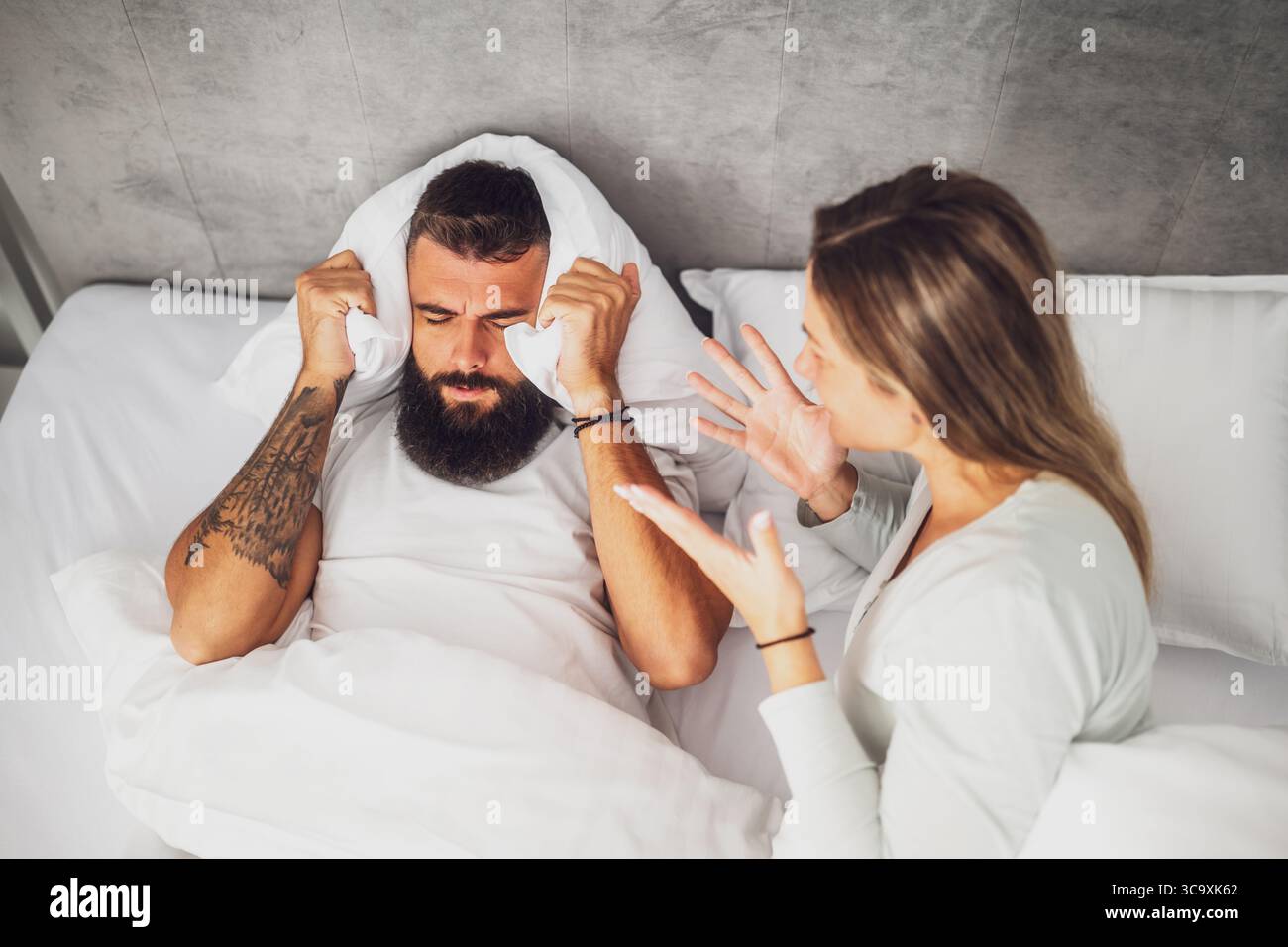 Couple is lying in bed and arguing. The woman is angry with the man ...