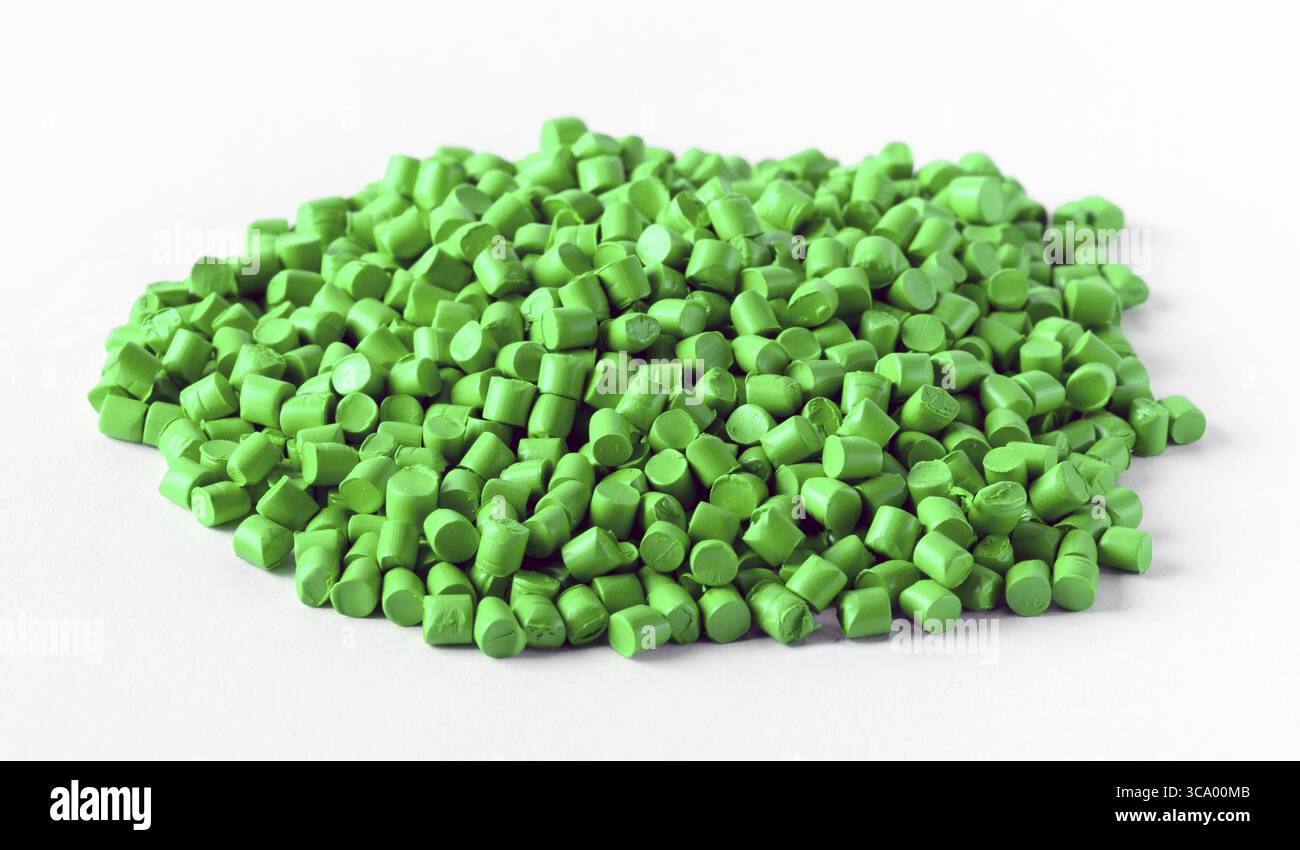 Green plastic granules forming a pile on a white background, ready to be processed and transformed into plastic products Stock Photo