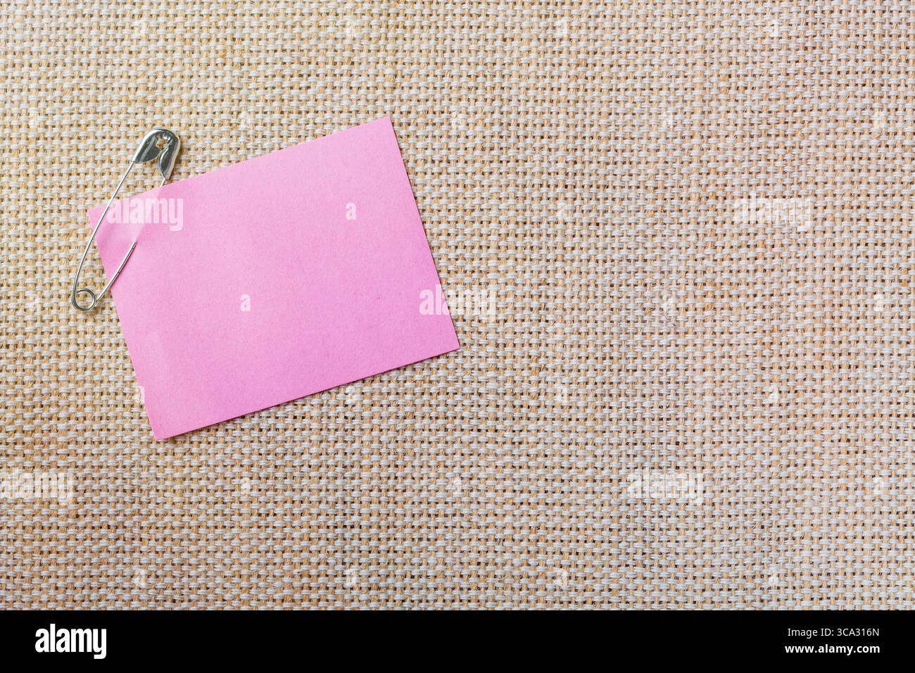 Pink sticker note with pin on canvas background. Stock Photo