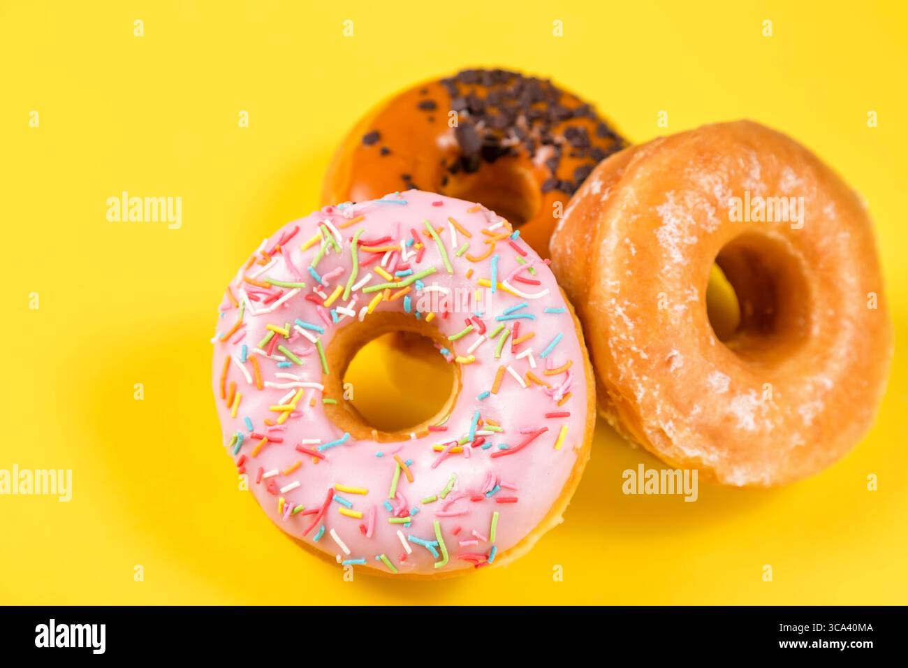 Three different donuts on yellow background. Close up image with selective focus. Stock Photo