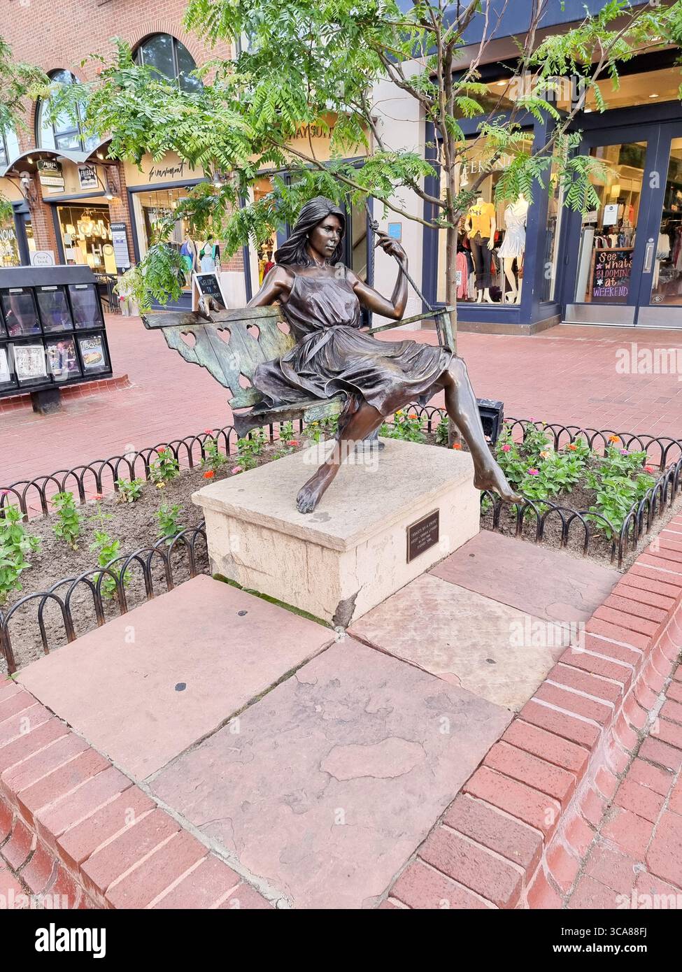 'Hearts on a swing' by George Lundeen, a bronze statue of a girl on a swing on Pearl street, Boulder CO, Colorado, U.S.A. - Smartphone Captured Stock Image