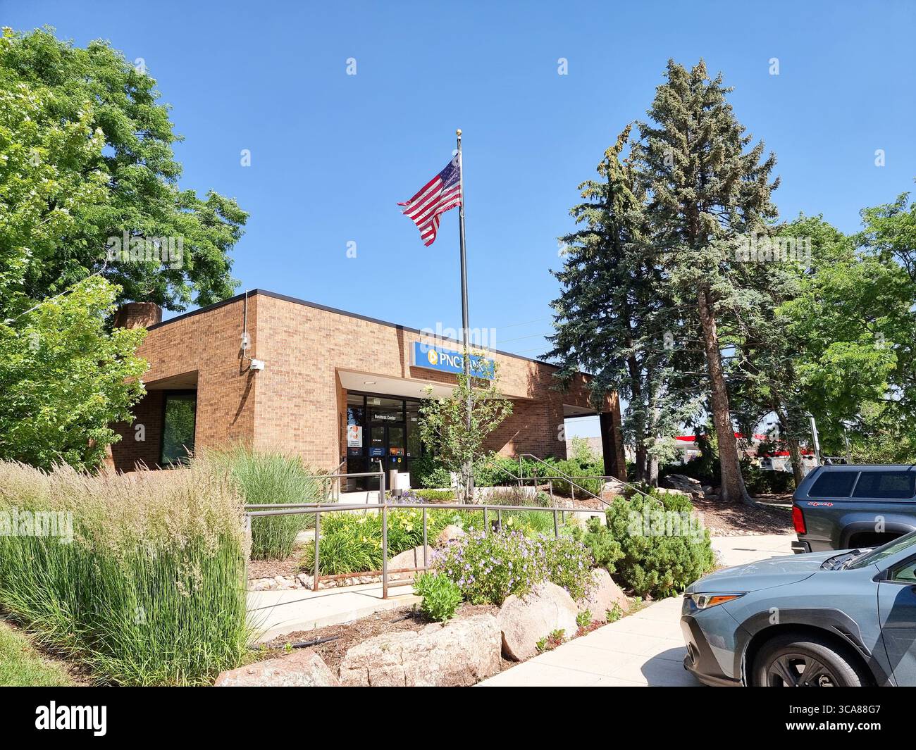 Rectangular building of PNC bank office in Boulder CO, Colorado, U.S.A. with American flag on a sunny day with blue sky - Smartphone Captured Stock Image