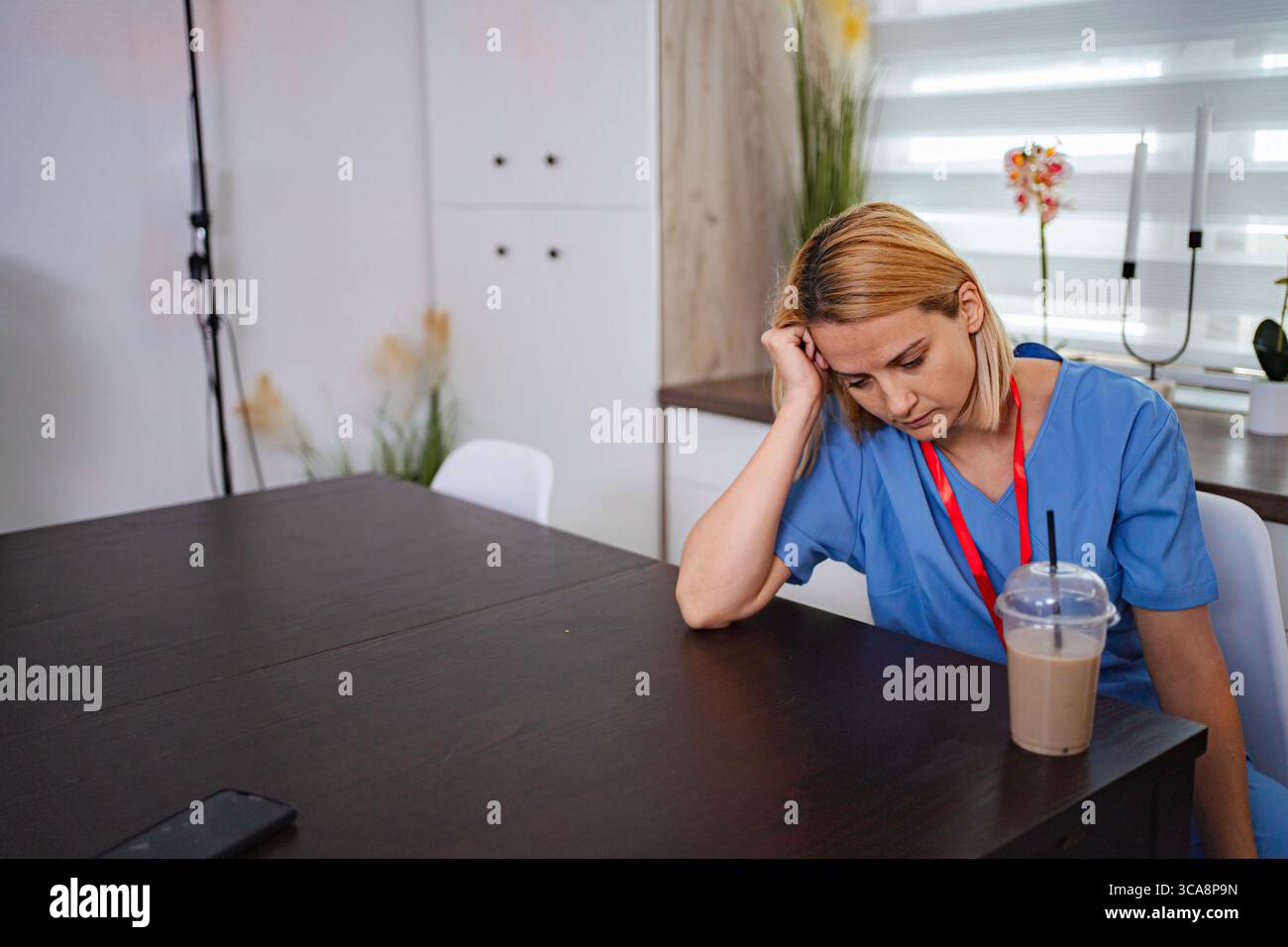 Exhausted nurse resting her head on a table during a break Stock Photo