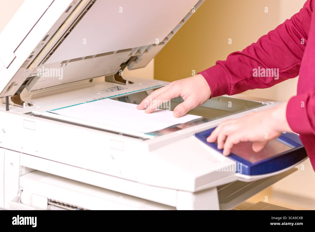 Man putting paper sheet on printer for scanning. Office work concept Stock Photo
