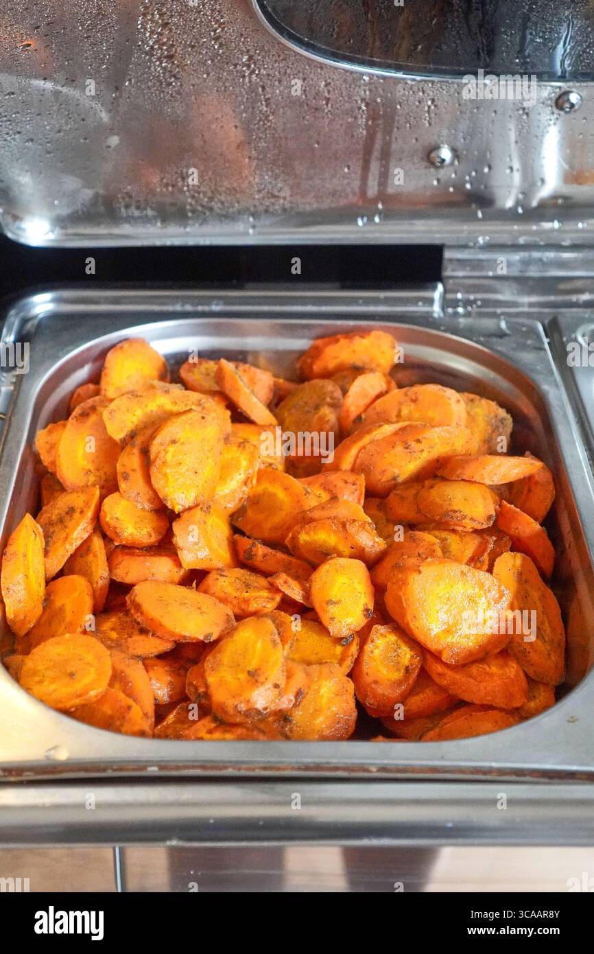 Hot roasted potatoes with golden crispy texture displayed on buffet warmer tray. Stock Photo
