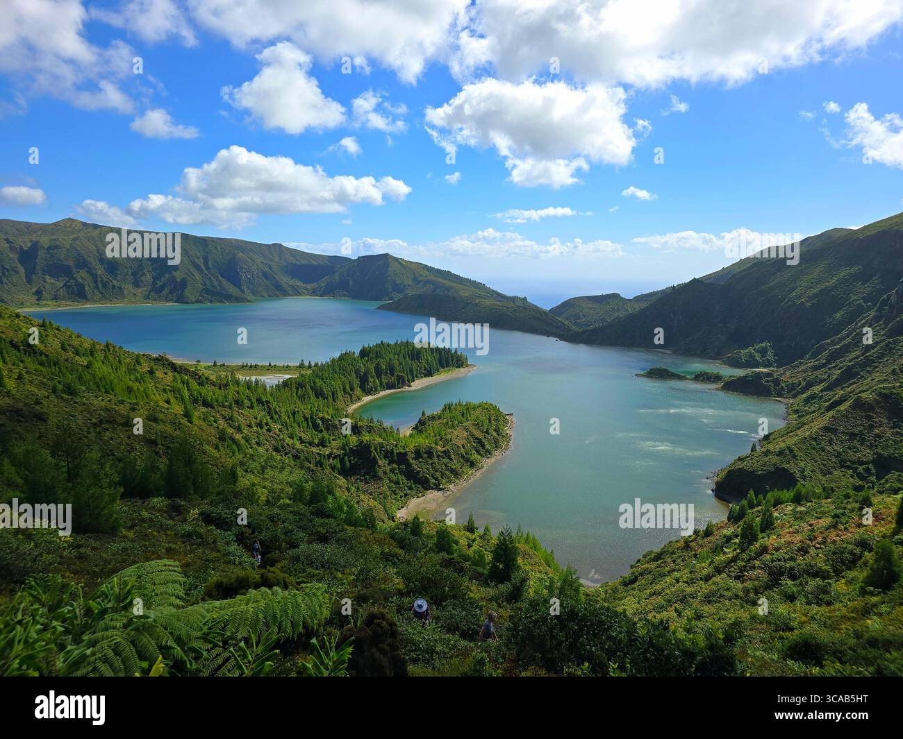 View of Lagoa do Fogo, a volcanic crater lake located on São Miguel Island in the Azores, Portugal, surrounded by lush green mountains under a partly - Smartphone Captured Stock Image