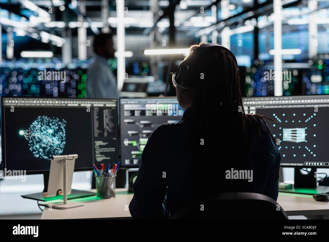 Data center admin uses AI visualization tool on PC to optimize resource allocation. Server farm employee uses artificial intelligence analysis software on computer to do maintenance Stock Photo