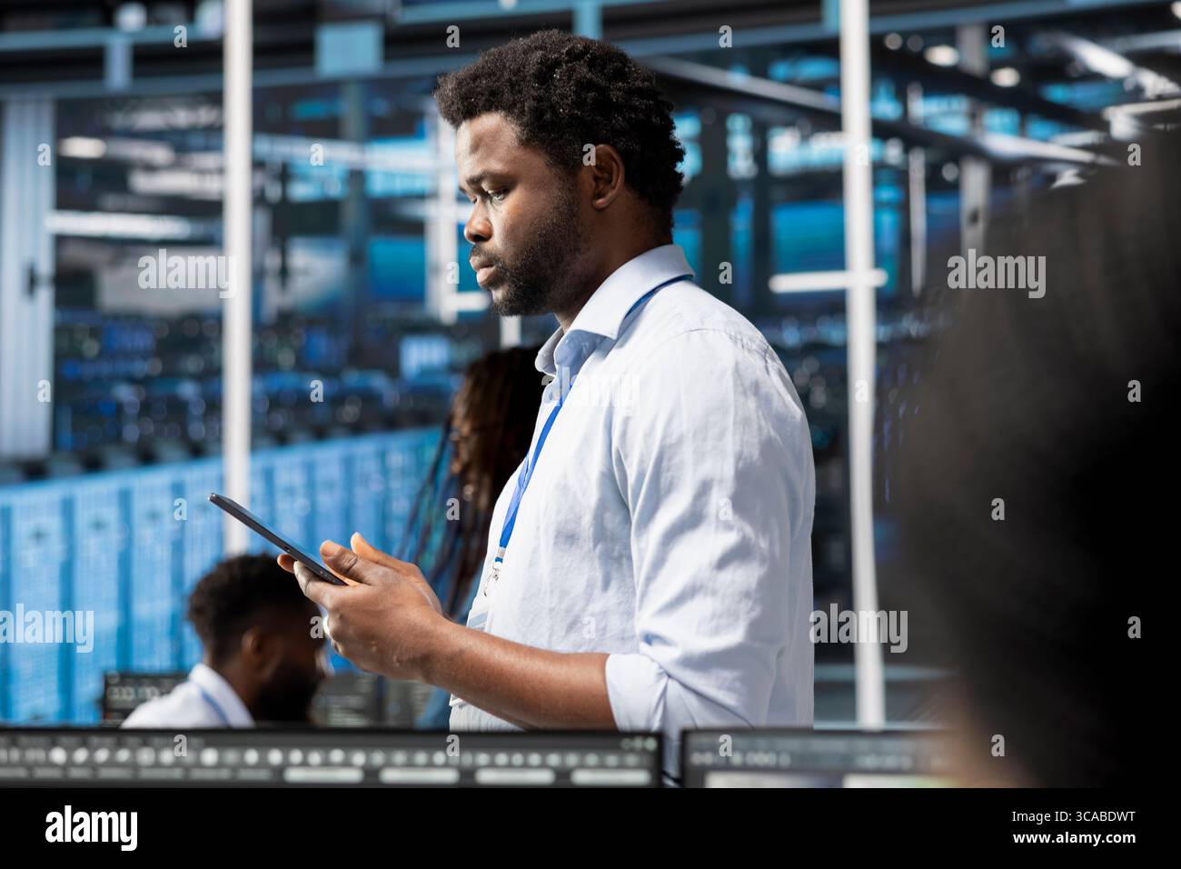 Manager walking through data center electronics providing processing resources for different workloads. Team leader using tablet to evaluate server rigs tasked with solving complex operations Stock Photo