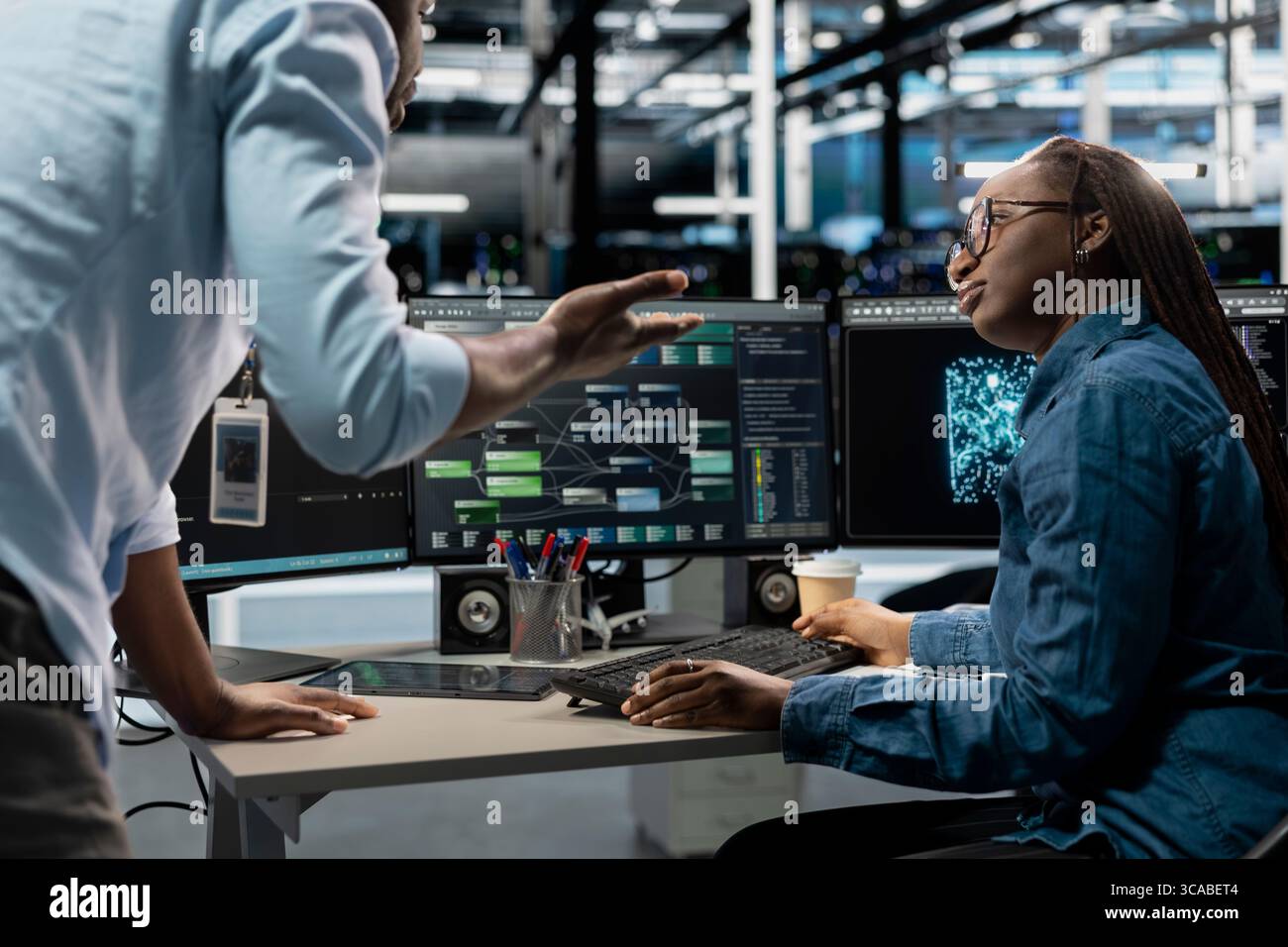 Server farm teamworking engineers doing brainstorming, looking at data analysis graph to reduce failures. Data center colleagues talking, working together using AI visualization dashboard Stock Photo