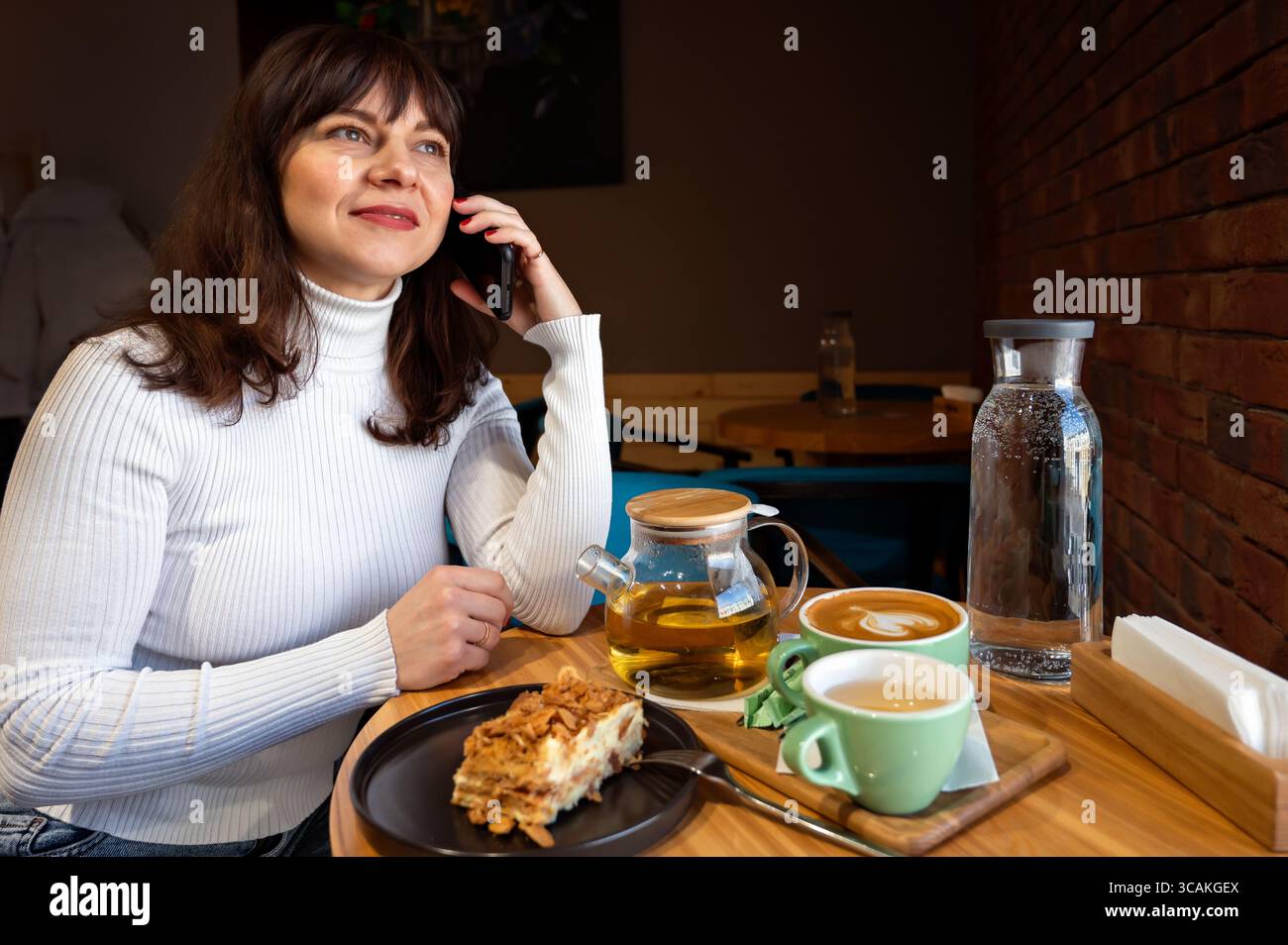 Young woman with a smartphone in a cafe. Coffee and tea. Stock Photo