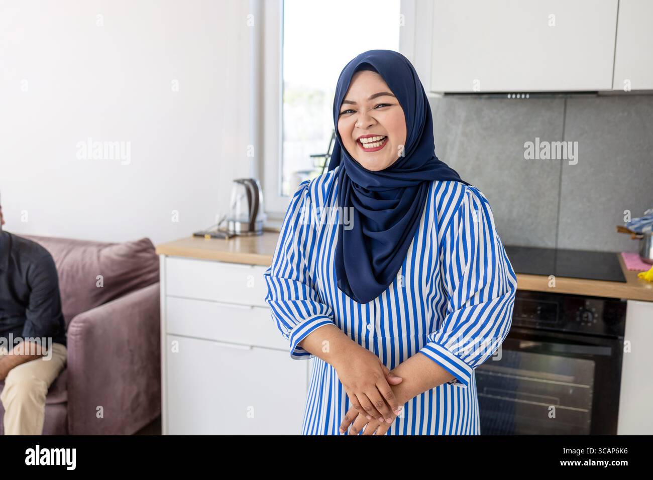 Muslim Woman Standing in Modern Kitchen Wearing Hijab Stock Photo