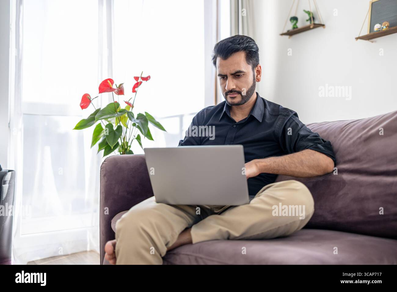 Man using laptop while sitting on a sofa at home Stock Photo