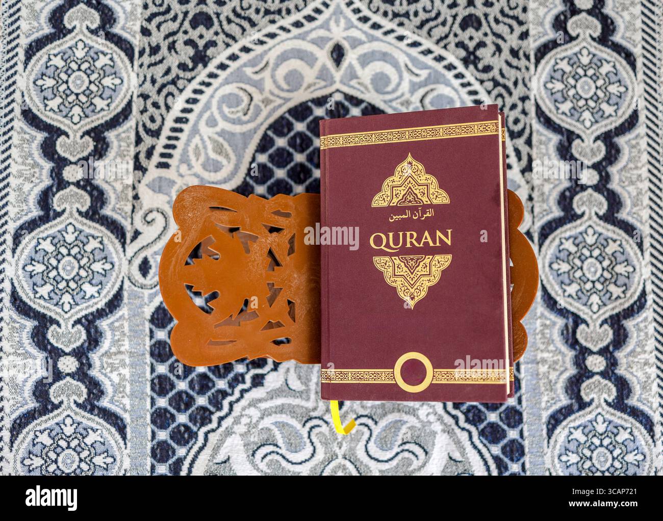 Holy Koran on Wooden Rehal Resting on Islamic Prayer Mat, Top View Stock Photo