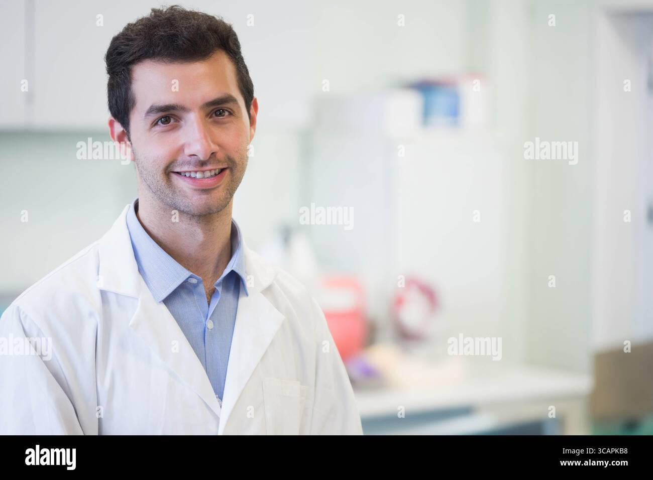 Male researcher wearing white lab coat standing in research laboratory ...