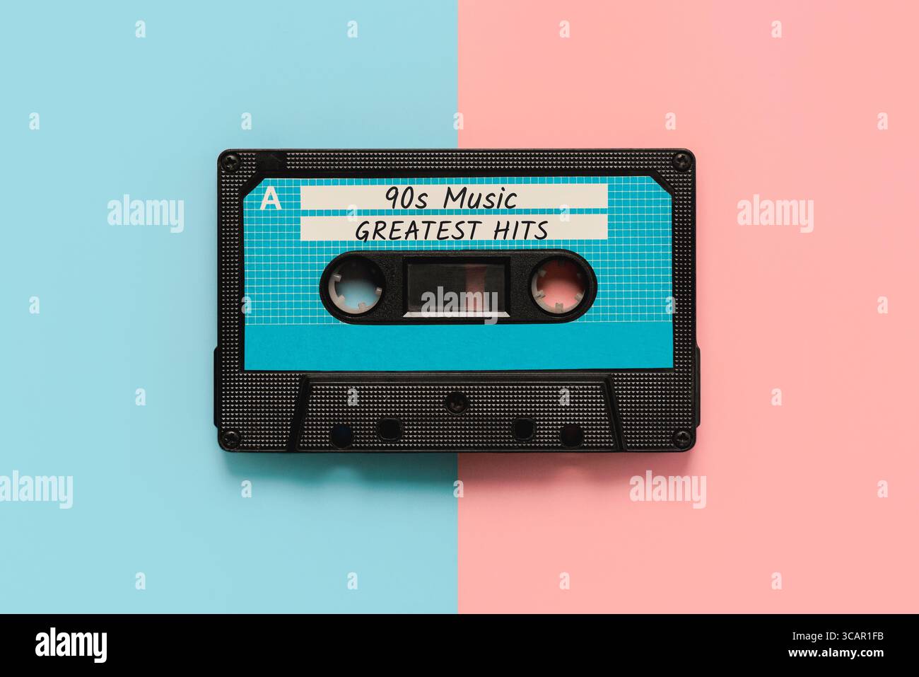 Top view of vintage audio cassette tape with the text 90s music greatest hits over pink and blue background. Retro music concept Stock Photo
