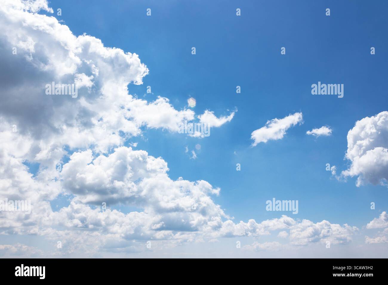 white fluffy clouds on the azure blue sky. cumulus cloudscape in bright light in summer. weather background for vacation on a sunny day. cloudy atmosp Stock Photo