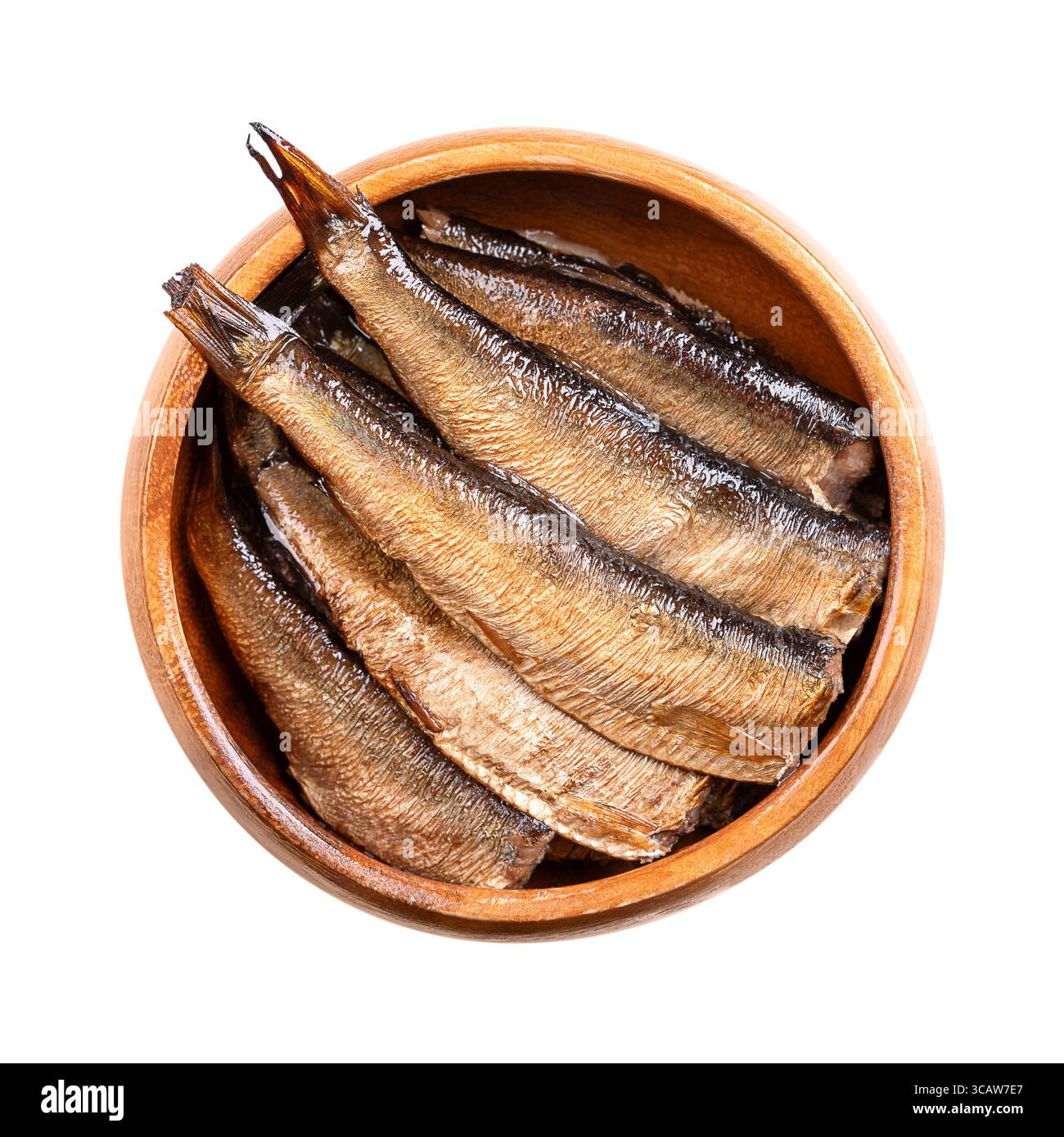 Smoked sprats in vegetable oil in a wooden bowl. Canned smoked European sprats in oil. Sprattus sprattus, a small saltwater fish. Stock Photo