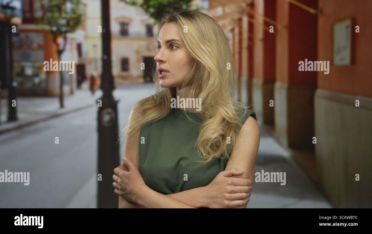 Woman with blonde hair appears nervous on a city street, crossing her ...