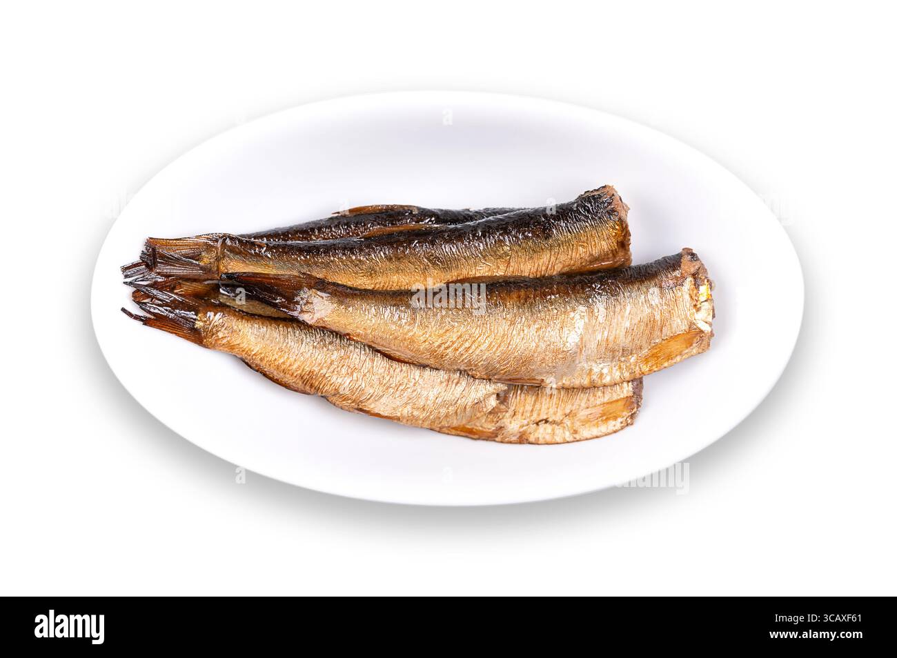 Smoked sprats in vegetable oil, in oval white bowl. Canned smoked European sprats in oil. Sprattus sprattus, small saltwater fish. Stock Photo
