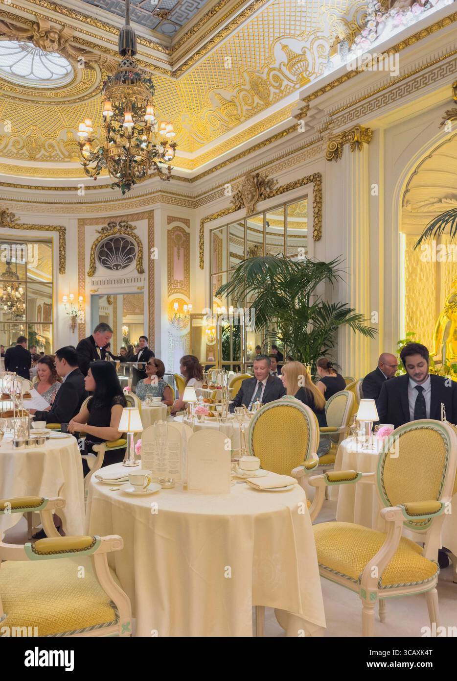 People enjoy the famous afternoon tea experience in the opulent Palm Court of The Ritz, a luxury five-star hotel in London, UK. Stock Photo