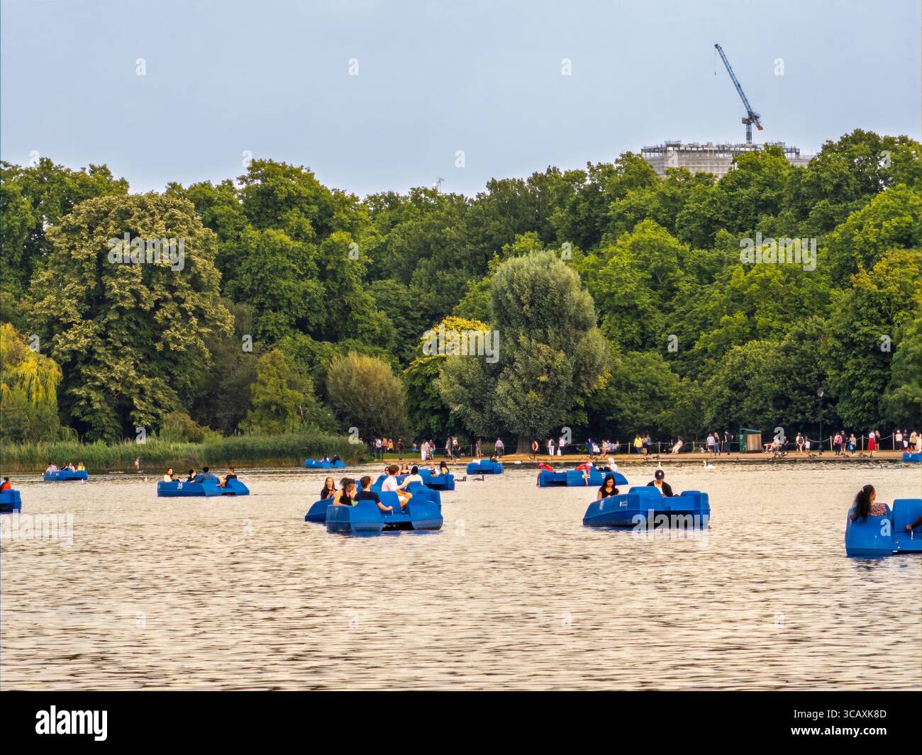 Tourists and Londoners enjoy boating in pedalos on the Serpentine lake in Hyde Park on a sunny summer day in London, UK. Stock Photo