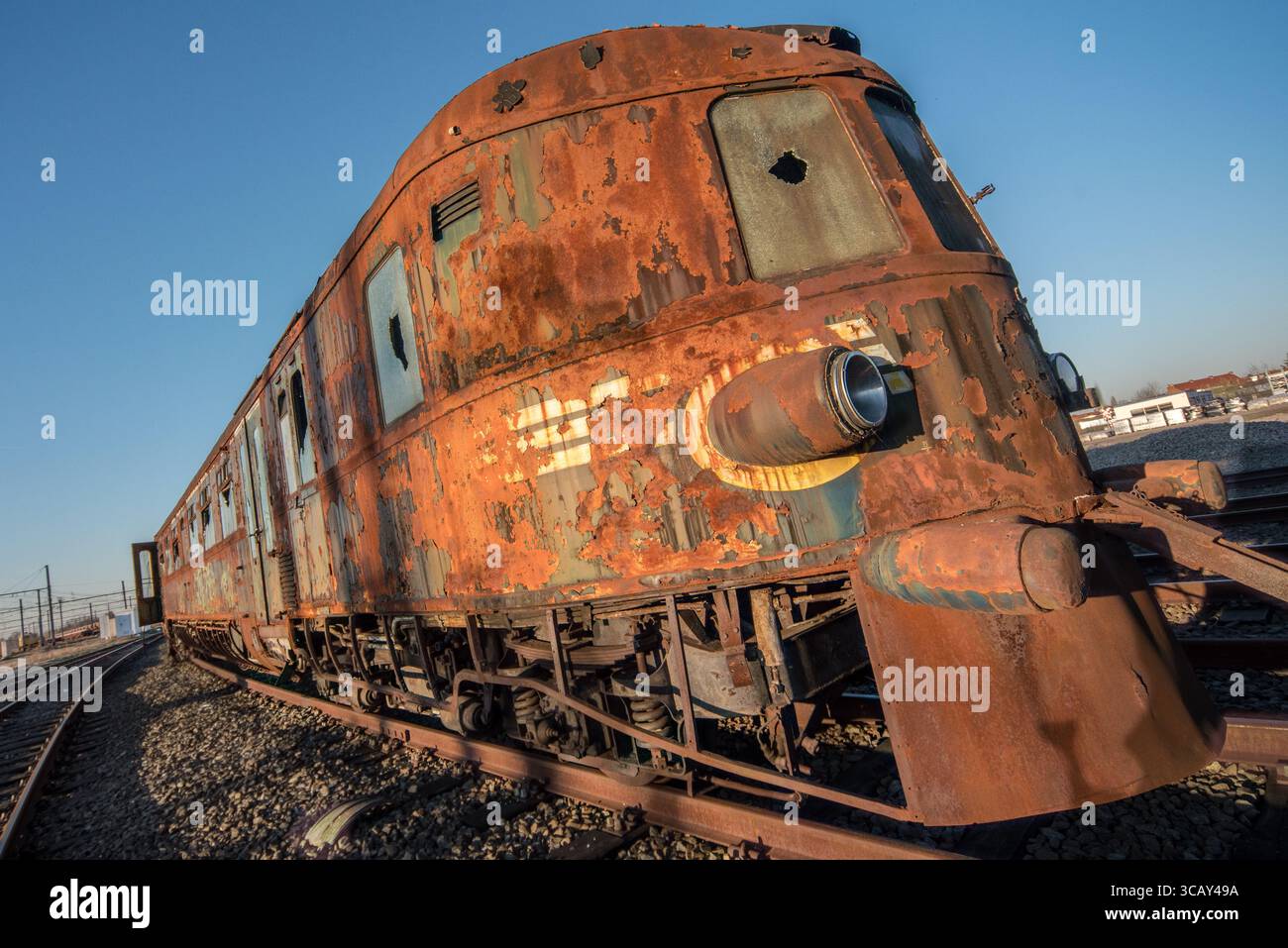 Rusty abandoned vintage train carriage with broken windows on railway tracks under clear blue sky Stock Photo