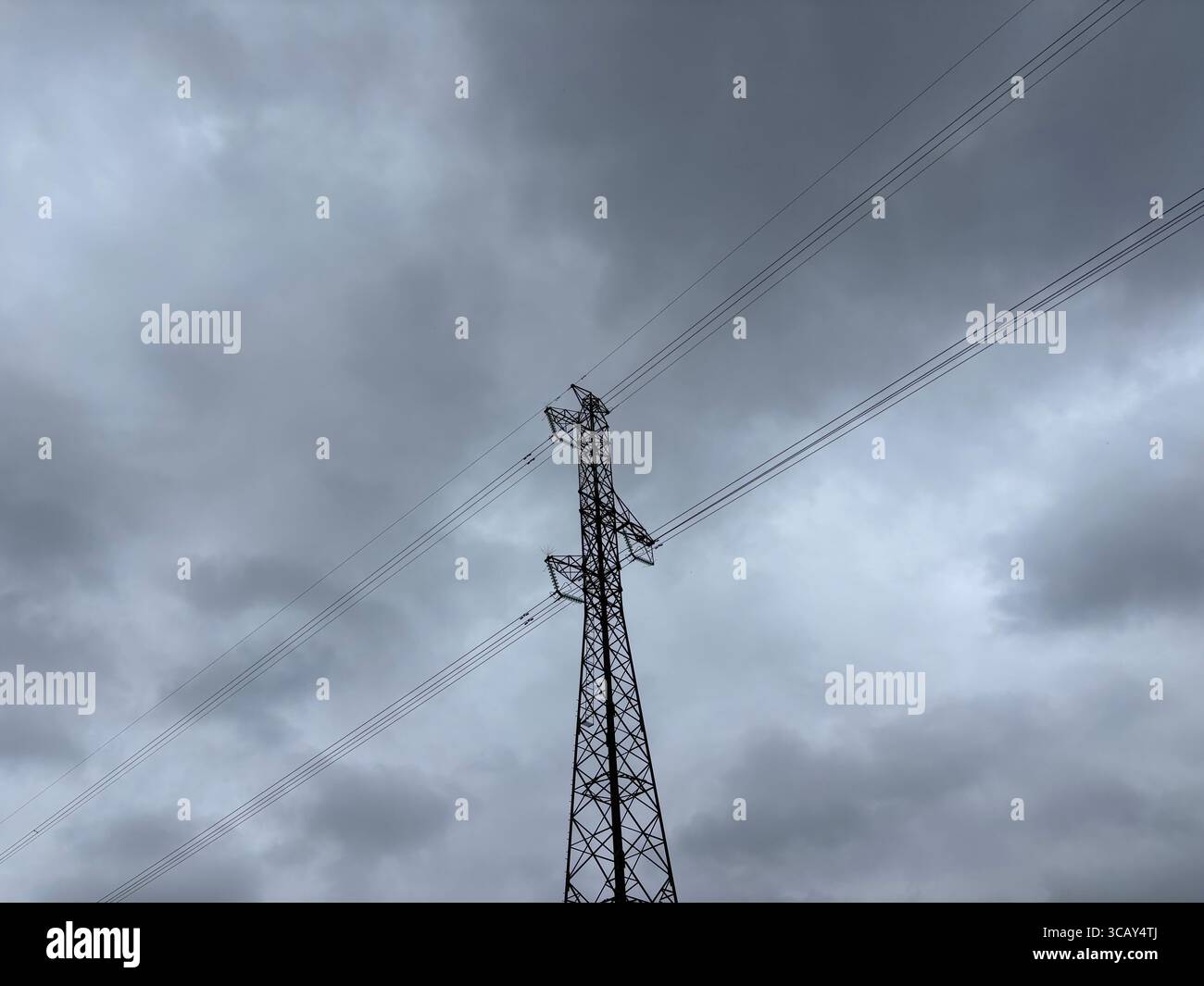 Electricity cables and electricity pylons against a grey cloudy sky. - Smartphone Captured Stock Image