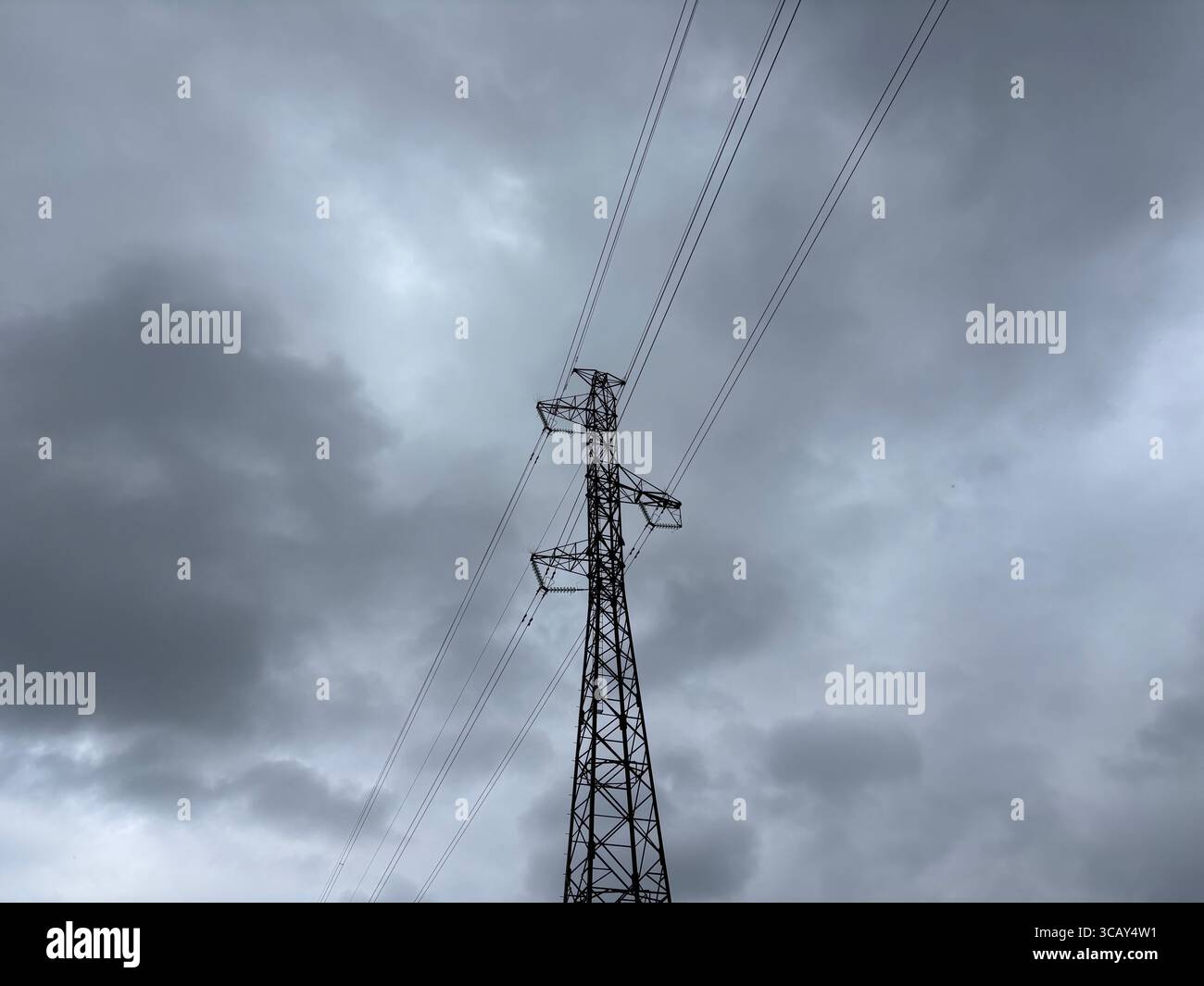 Electricity cables and electricity pylons against a grey cloudy sky. - Smartphone Captured Stock Image