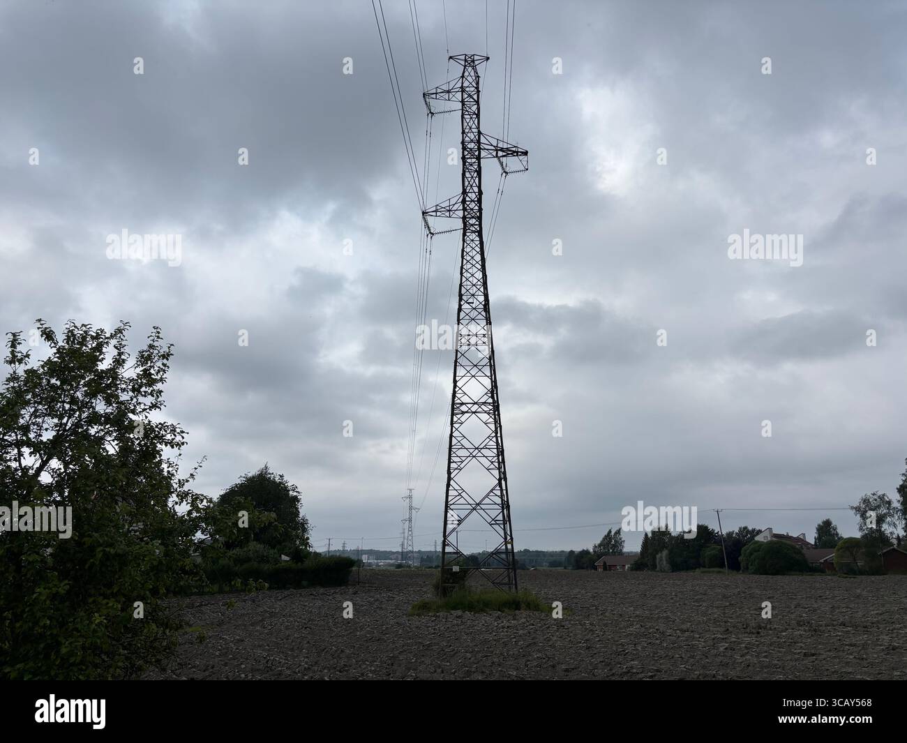 Electricity cables and electricity pylons against a grey cloudy sky. - Smartphone Captured Stock Image