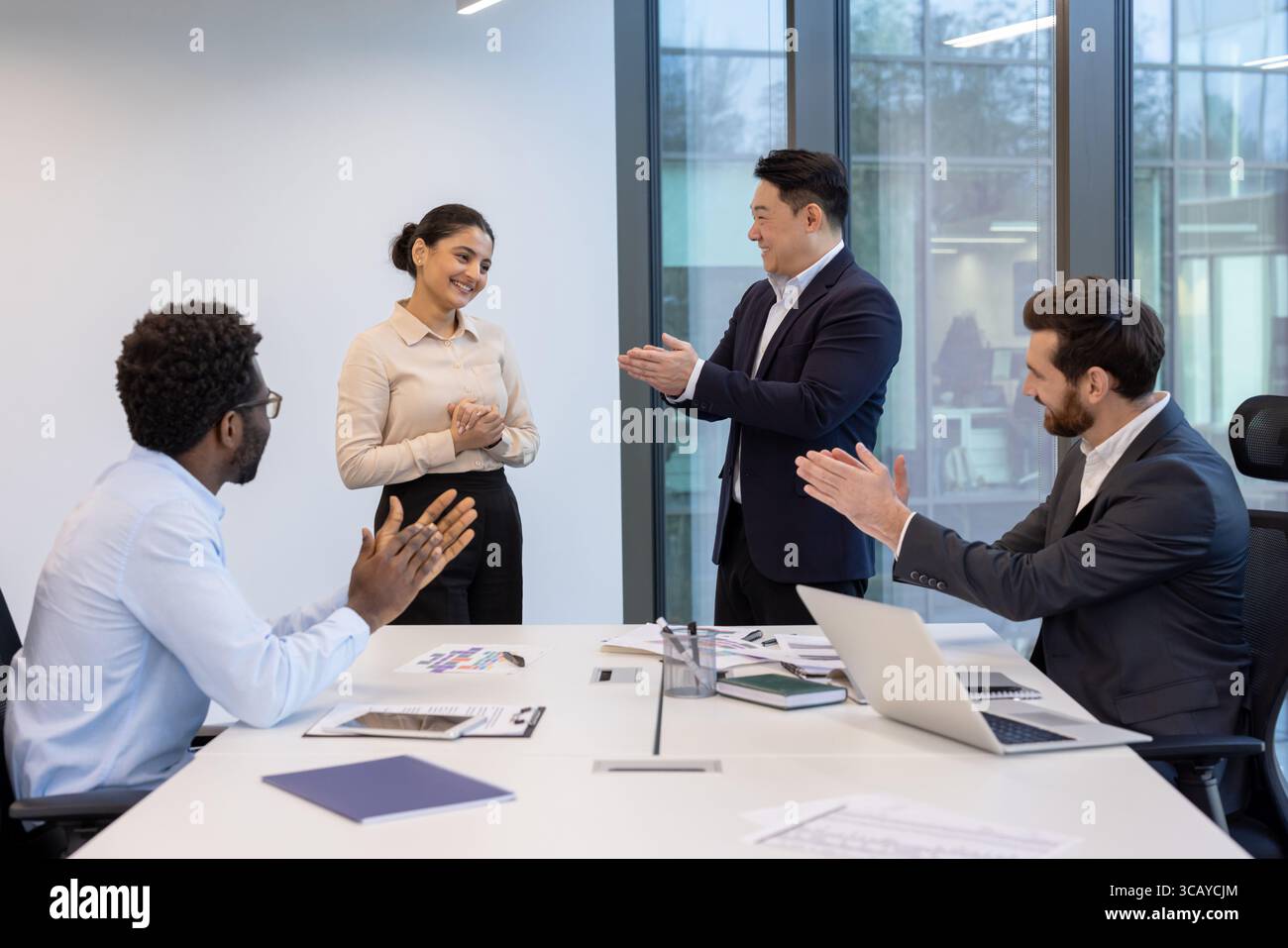 Employees engaging in a professional meeting, applauding colleague for ...