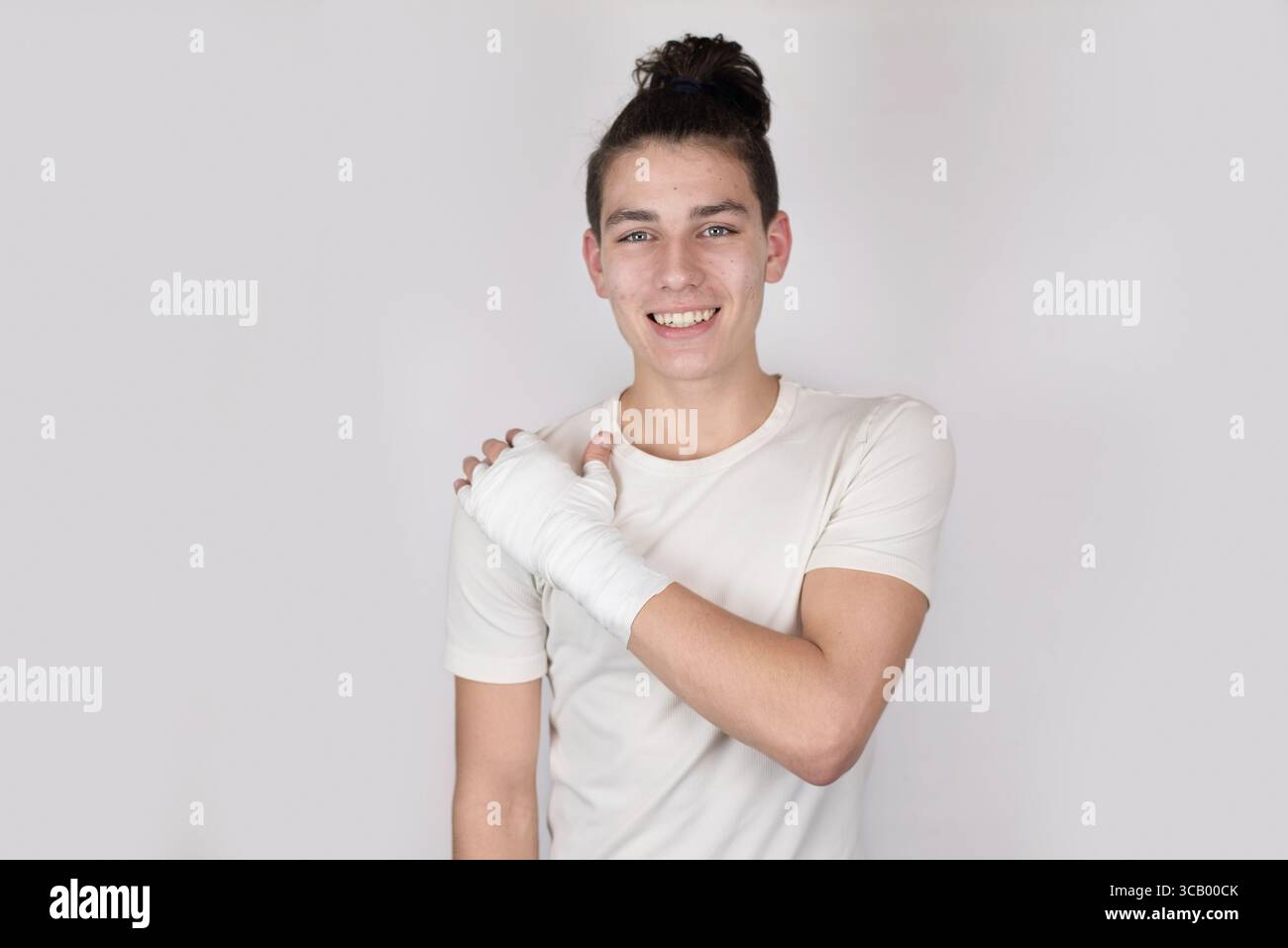 The guy injured his arm during training and now has a bandage on his arm. A young man with a friendly smile, showcasing resilience and optimism Stock Photo