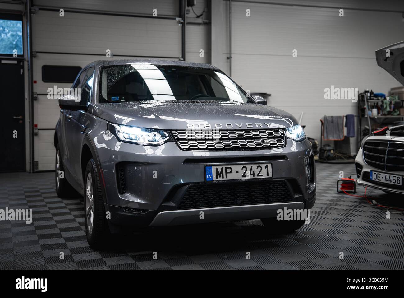 Silver Range Rover Discovery and White Mercedes in Car Shop Garage Stock Photo