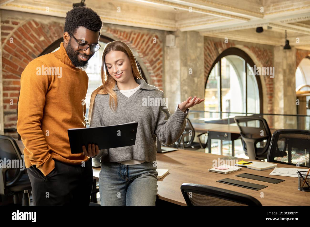 Multiethnic team members collaborating and smiling while working on business project Stock Photo