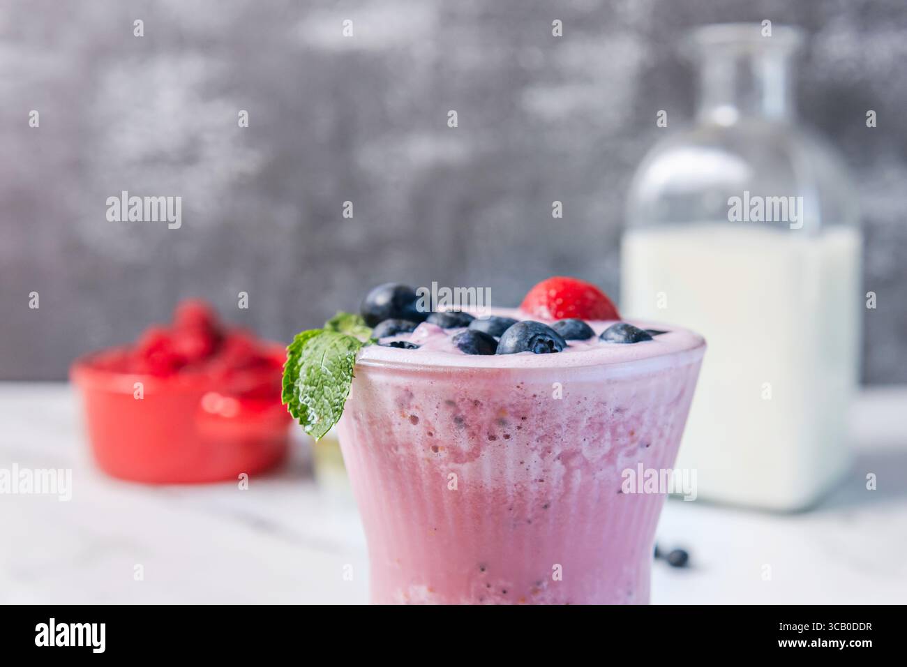 Blueberry and Raspberry Smoothie: A deep purple hue in a clear glass, with a long spoon inviting you to enjoy its silky texture Stock Photo