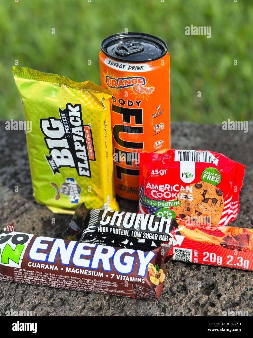 Assorted energy snacks and drink placed on grass for outdoor activity or fitness fueling. - Smartphone Captured Stock Image