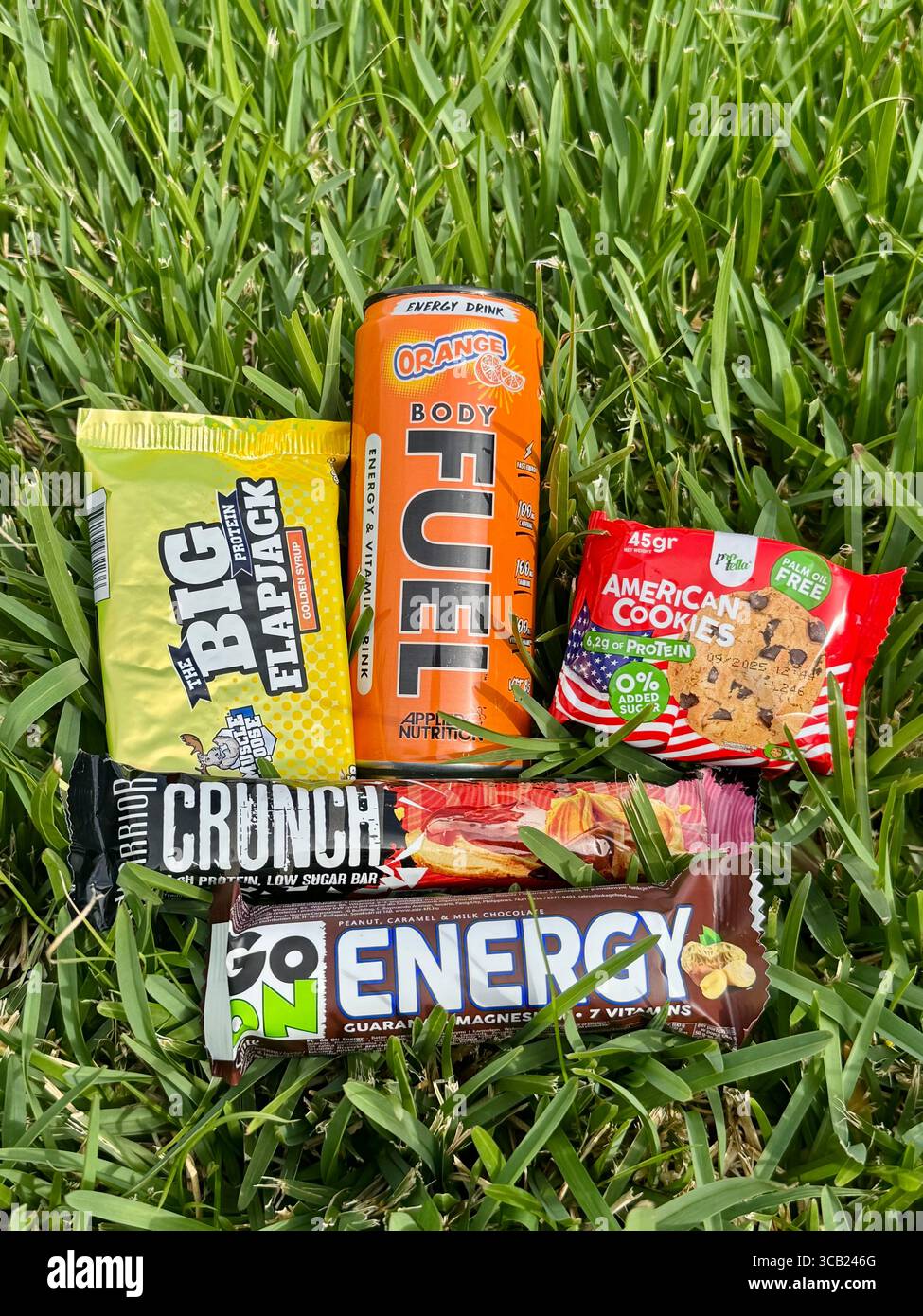 Assorted energy snacks and drink placed on grass for outdoor activity or fitness fueling. - Smartphone Captured Stock Image