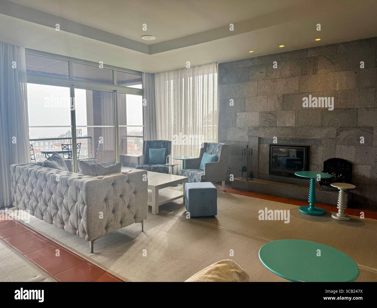 Elegant hotel lounge with tufted sofa, modern armchairs, fireplace, and large windows overlooking scenic views at Lince Nordeste Country Hotel. - Smartphone Captured Stock Image