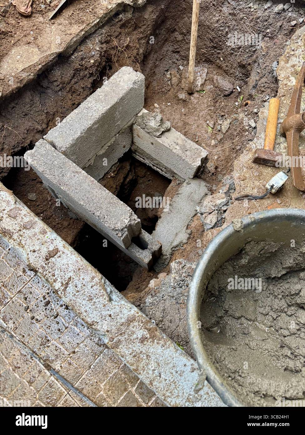Construction of a small septic tank system with concrete blocks and excavation tools on-site. - Smartphone Captured Stock Image