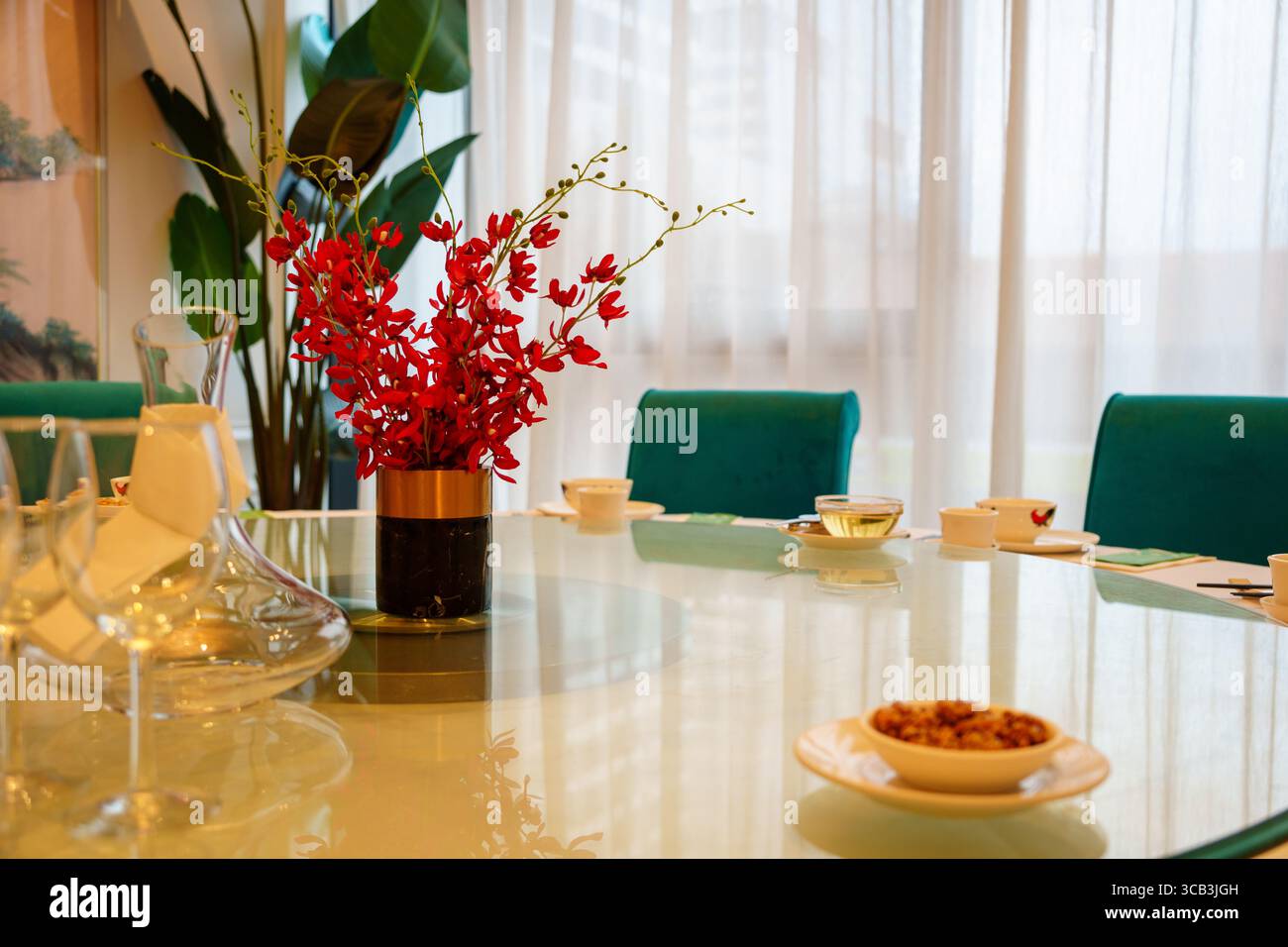 elegant restaurant table setting with red orchids centrepiece, teal chairs and tea cups ready for service Stock Photo