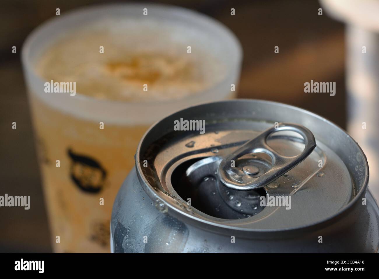 Close-up of opened aluminum can with foamy beer in plastic cup Stock Photo