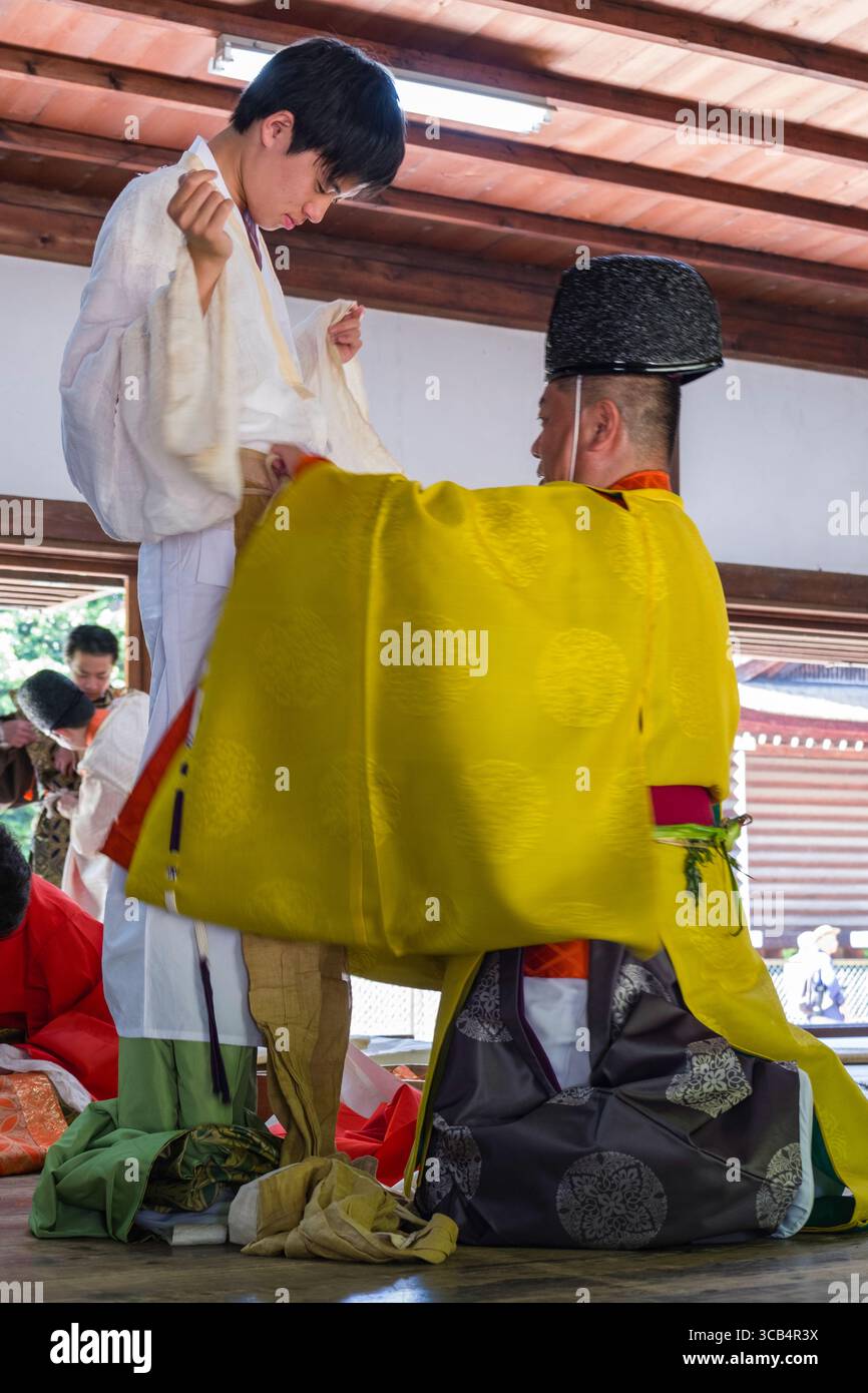 A young individual is being helped with traditional Japanese attire ...