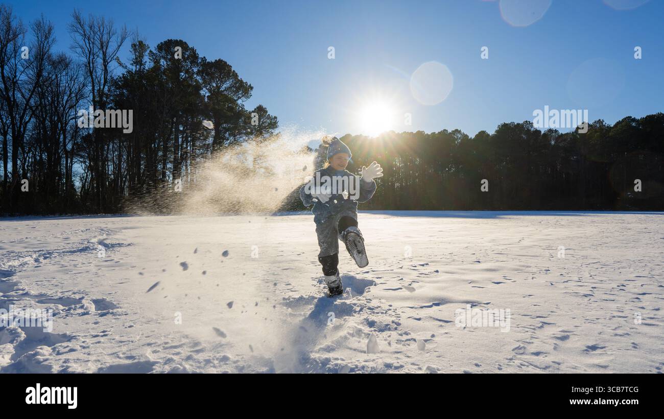 Snowball fight. Kid throws a snowball. Child runs through falling snow ...