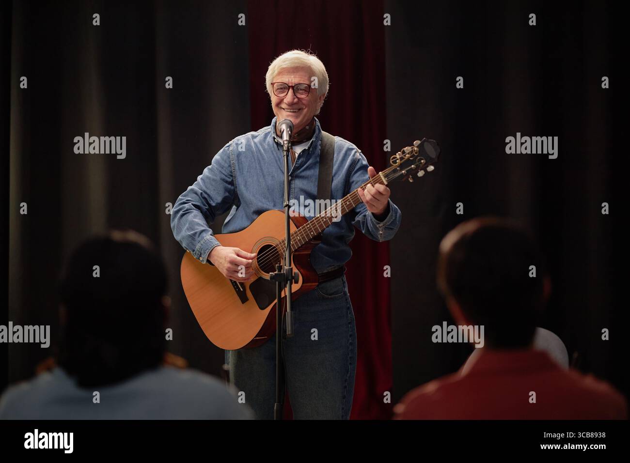 Elderly Caucasian Man Performing Acoustic Guitar Song during Talent Competition Stock Photo