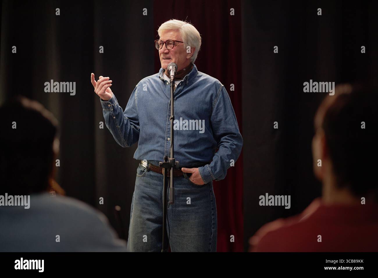 Senior Caucasian Man Entertaining Audience with Storytelling at Talent Competition Stock Photo