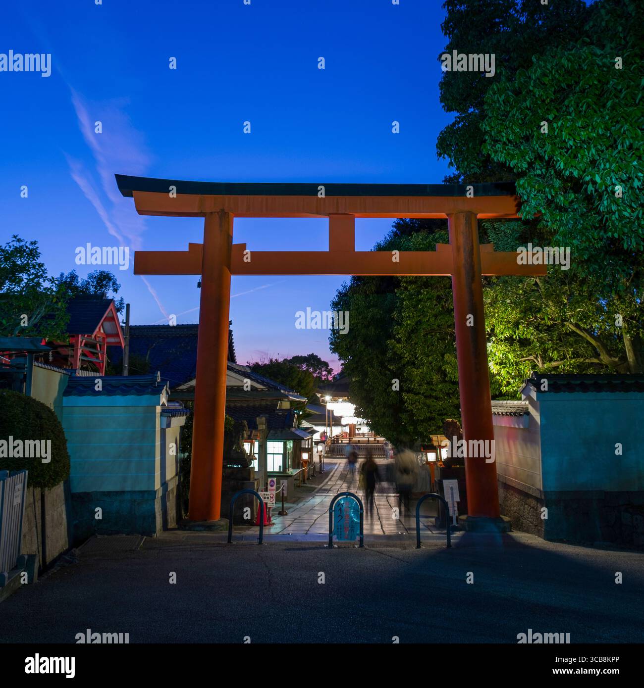 An iconic red torii gate stands illuminated during dusk near Yasaka ...