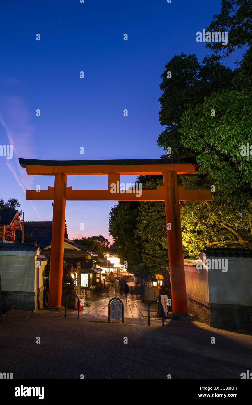A glowing red torii gate welcomes visitors to Yasaka Shrine during ...