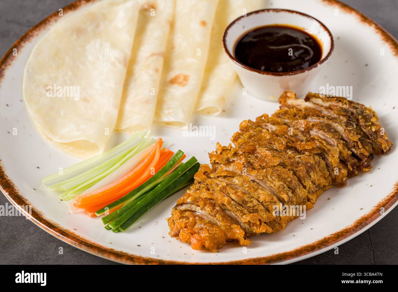 Sliced crispy duck served with pancakes, hoisin sauce, and vegetables Stock Photo