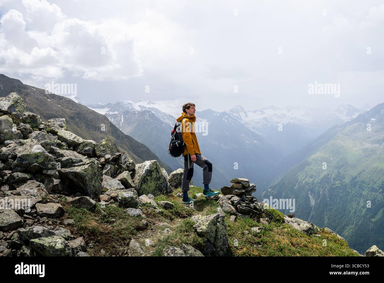 Man in yellow jacket standing on alpine summit in Austria Stock Photo